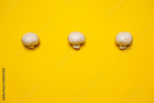 Fresh whole champignon mushrooms on a yellow background. Cool minimal flat lay, copy space. (ID: 584033245)