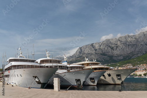 Fototapeta Naklejka Na Ścianę i Meble -  Huge tourist carts in the bay. big plan. In the background is the city of Makarska. Croatia. High mountains