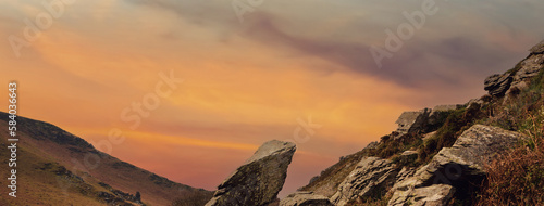Wide panoramic view of the mountains in the evening at sunset with a beautiful orange sky in the background © Armands photography