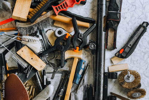 A pile, a lot of household tools are scattered randomly on the table in the mechanic's workshop. Close-up photo, household junk, top view. The concept of locksmith work.