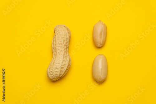Whole peanut in the shell and peeled on a yellow background. Protein and healthy dried fruit. Cool minimal flat lay, copy space  (ID: 584040297)