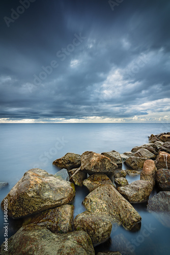 View of the lake from the boulders shore with impending rain and storm clouds at IJsselmeer Netherlands near the village Urk in Flevoland