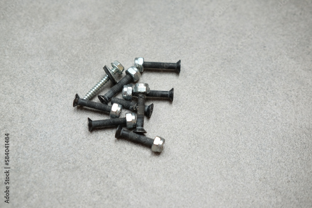 Metal screws and bolts on a gray background Metal screws and bolts on a gray background