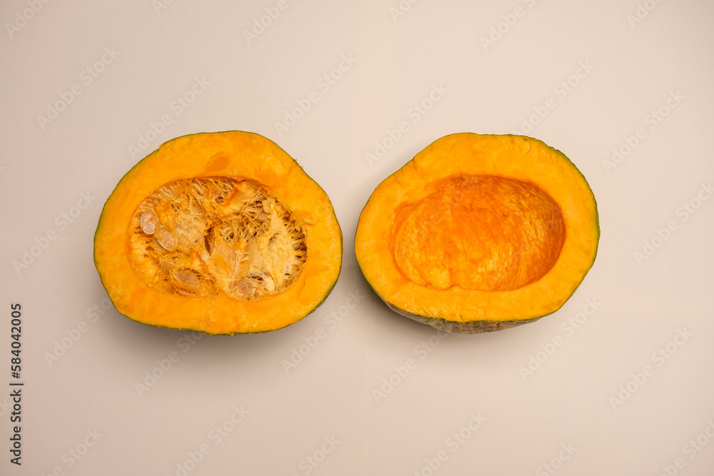 A juicy organic pumpkin cut in half on a white background. Seasonal food typical of autumn A juicy organic pumpkin cut in half on a white background. Seasonal food typical of autumn