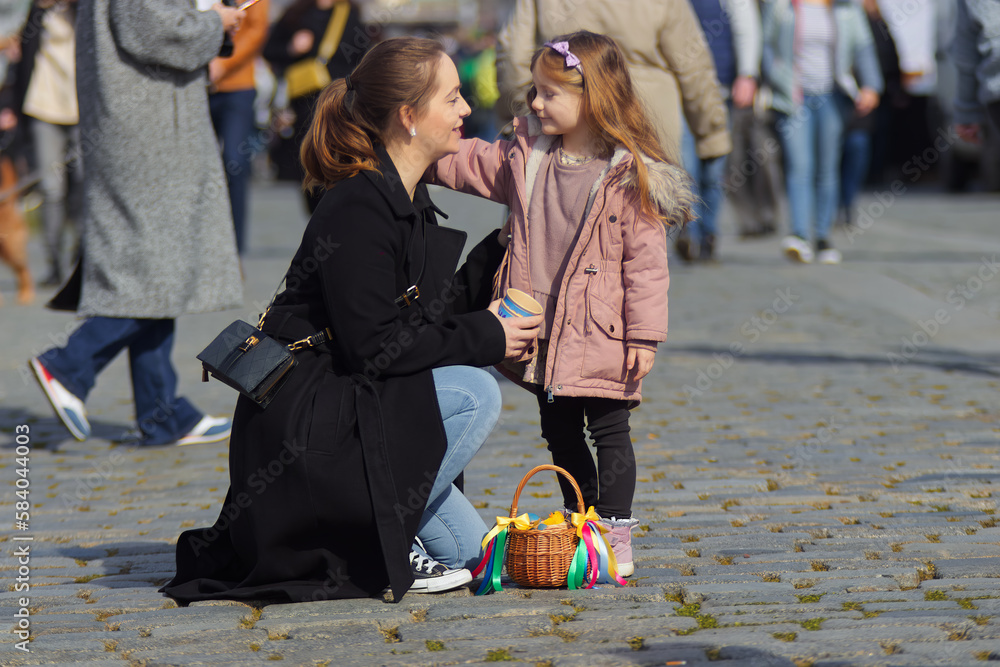 Young mother with her little daughter at the Easter market in Prague, a purchased basket with Easter decorations on the grund. Sunny spring day, no AI. Young mother with her little daughter at the Easter market in Prague, a purchased basket with Easter decorations on the grund. Sunny spring day, no AI.