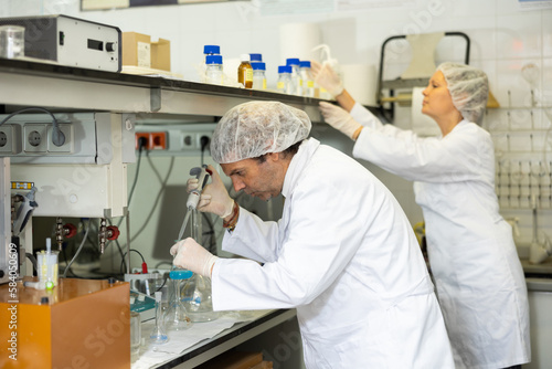 Concentrated man and woman chemists checking reagent in test tube during scientific research in modern laboratory