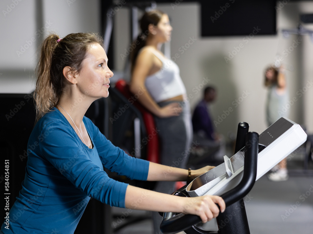 Fototapeta premium Sporty woman doing cardio workout out, training on exercise bike