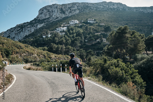 A professional cyclist's epic mountain ride.Male cyclist riding in the mountains.Man cyclist wearing cycling kit and helmet.Beautiful motivation image of an athlete.Descending the mountain.Xàbia,Spain