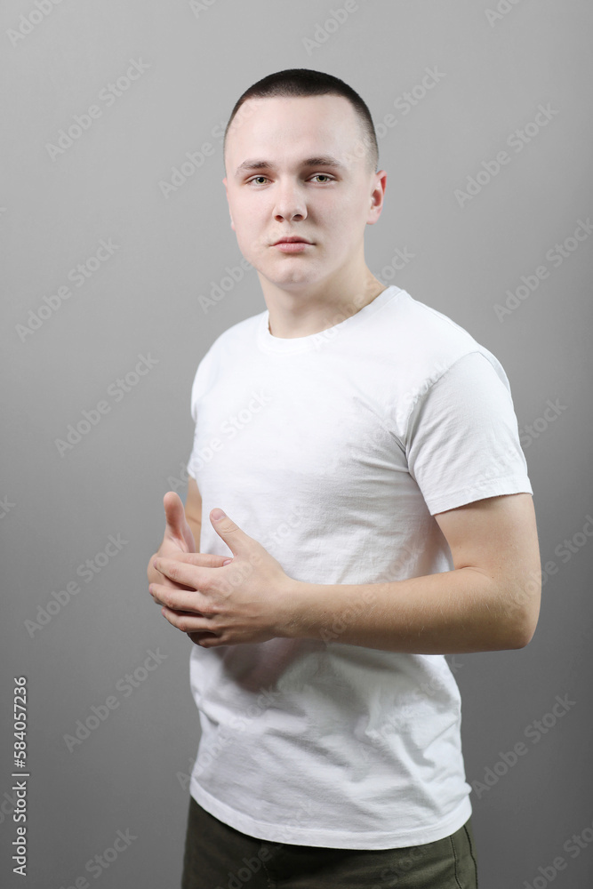 Studio portrait of handsome confident young man in casual white t shirts with mock up crossed his hands and looking at camera isolated on grey background. Studio portrait of handsome confident young man in casual white t shirts with mock up crossed his hands and looking at camera isolated on grey background.