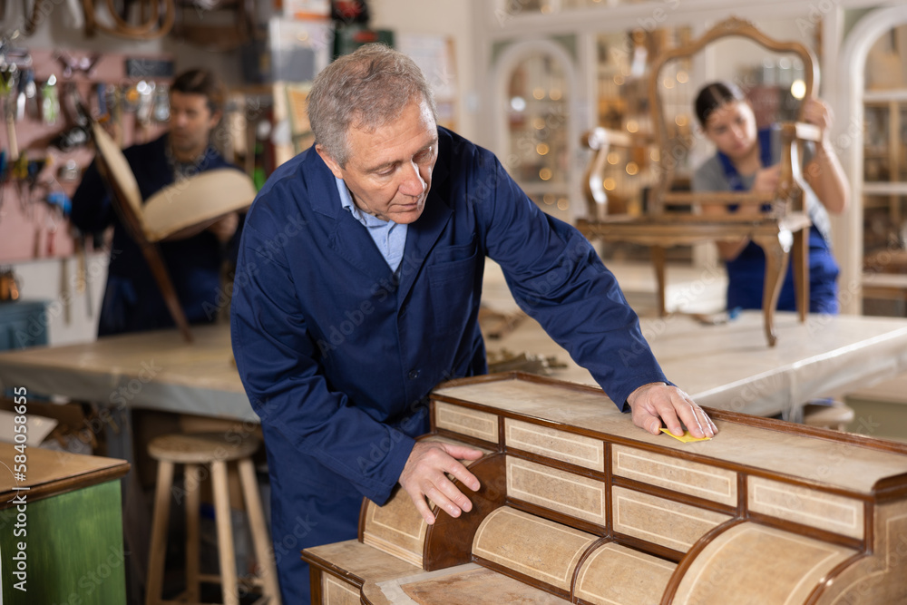 Senior male furniture workshop worker designing vintage chest of drawers