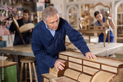 Senior male furniture workshop worker designing vintage chest of drawers