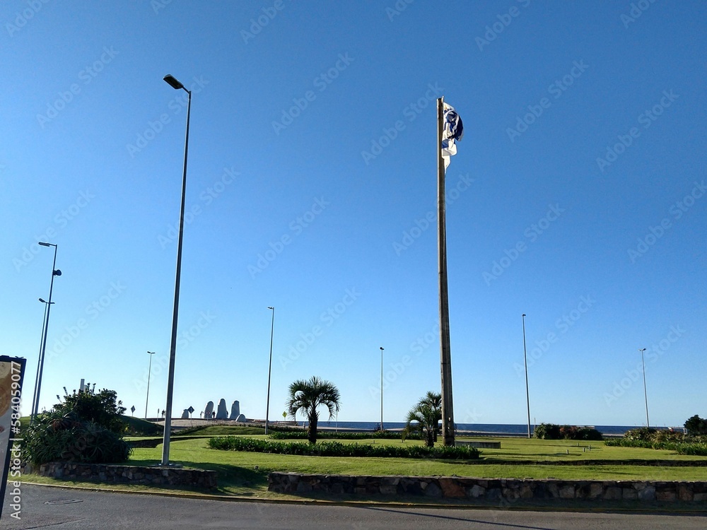 Uruguay flag with Los Dedos Monument in the background