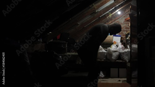 An old room with an attic. The pantry is a mess. A man in an old room dimly lit by a light bulb