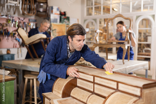 Male carpenter working on making vintage commode in workshop