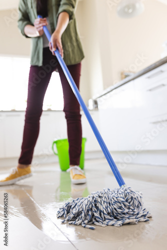 Low section of young caucasian woman cleaning floor with mop at home, copy space
