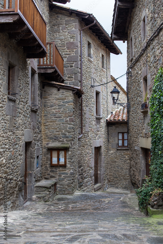 Calle de pueblo de montaña con ventanas balcones y farola
