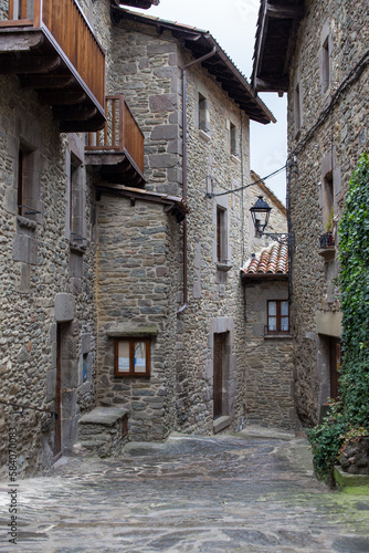 Calle de pueblo de montaña con ventanas balcones y farola