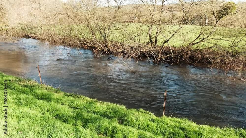 A river in France in the countryside. Sunny day, shore covered with green grass, calm water flow. A river in France in the countryside. Sunny day, shore covered with green grass, calm water flow.