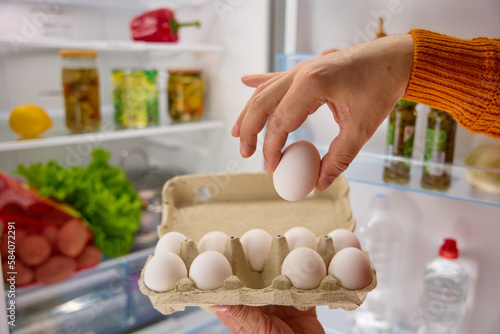 man hands take white chicken eggs from the fridge