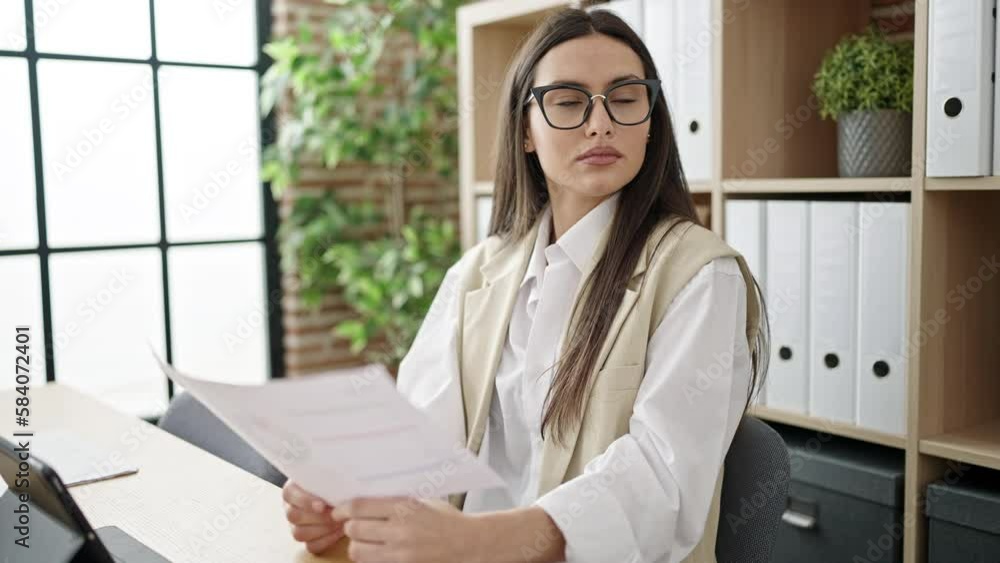 Young beautiful hispanic woman business worker using touchpad reading document at office Young beautiful hispanic woman business worker using touchpad reading document at office