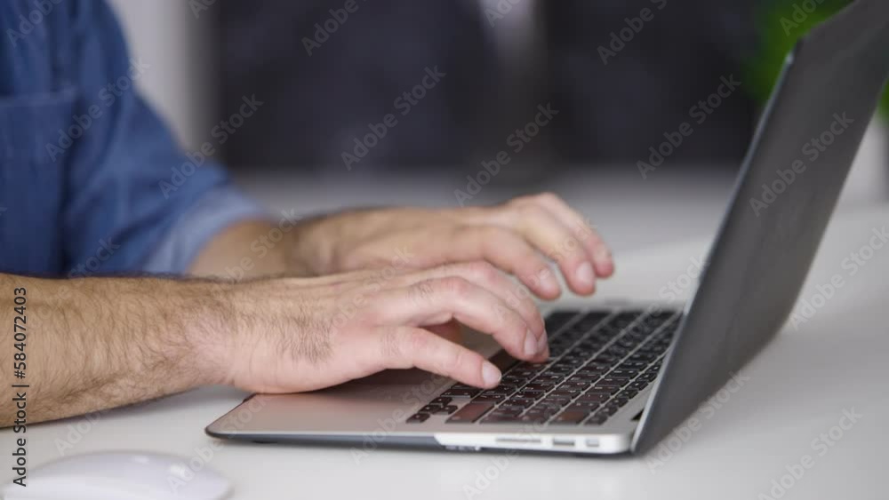 Close-up of a man working on a laptop at home in the office. Male hands typing on a modern laptop Close-up of a man working on a laptop at home in the office. Male hands typing on a modern laptop