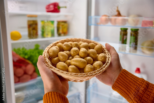 male hands put a basket of organic potatoes in the fridge