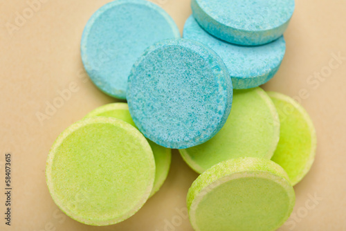 Green and blue soluble tablets on beige background