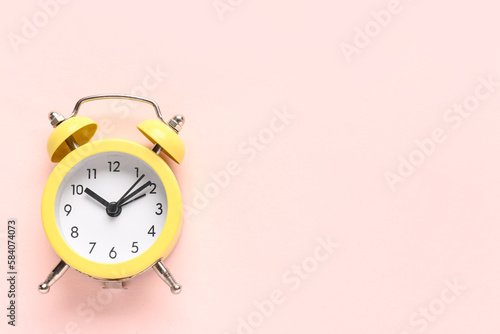 Yellow alarm clock on pink background