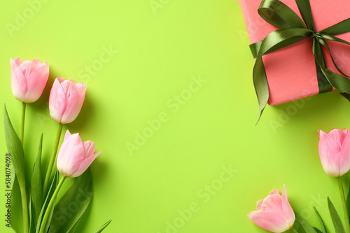 Flat lay composition with tulips and gift box on green background. Happy Mother's Day concept.