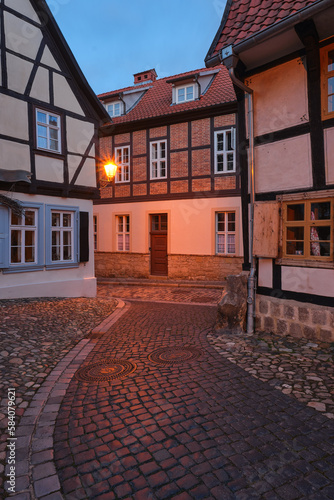 An historical streetlight gives a warm illumination light at historical timbered houses in Quedlinburg  Germany. The light is reflected on the historical pavement