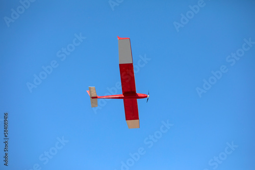 A radio controlled powered model glider soars against a blue sky background.