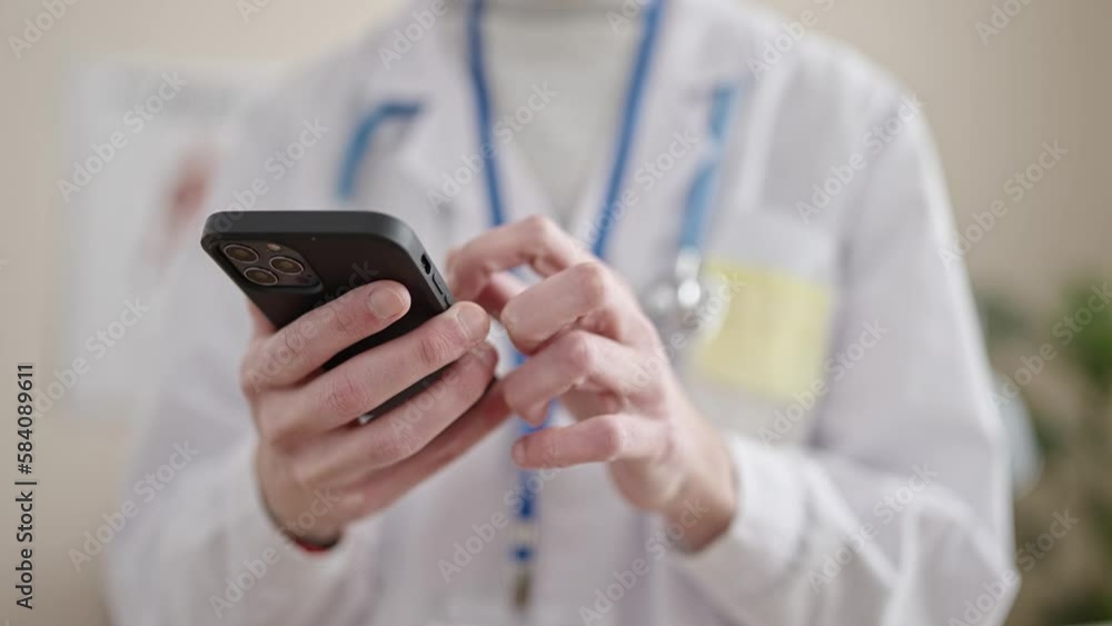 Young hispanic man doctor using smartphone at clinic Young hispanic man doctor using smartphone at clinic