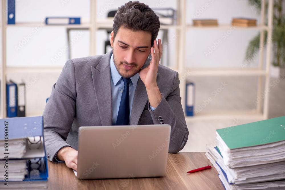 Young male employee and too much work in the office Young male employee and too much work in the office