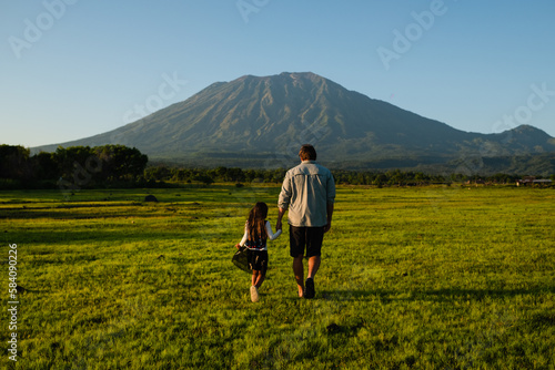 Wallpaper Mural Father and daughter are walking on the lawn, holding hands, rear view, against the backdrop of a beautiful mountain. Torontodigital.ca