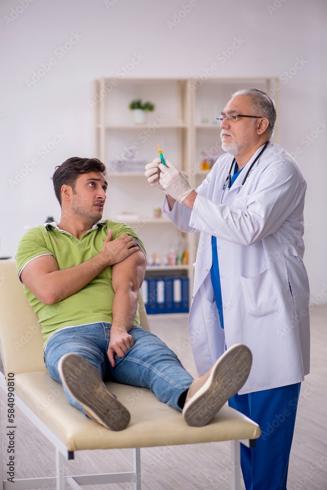 Fototapeta premium Young male patient visiting old male doctor in vaccination conce