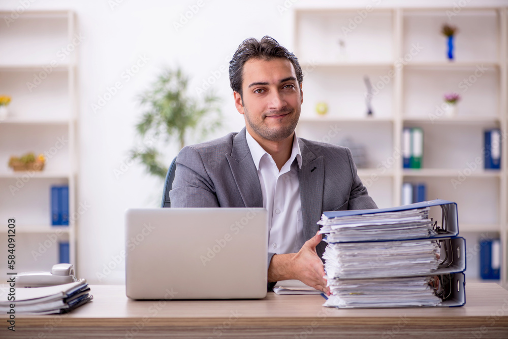 Young male employee and too much work in the office Young male employee and too much work in the office