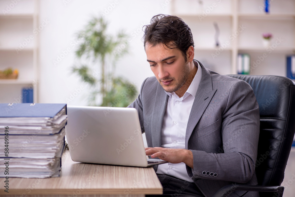 Young male employee and too much work in the office Young male employee and too much work in the office