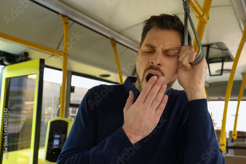 Sleepy tired man yawning in public transport photo