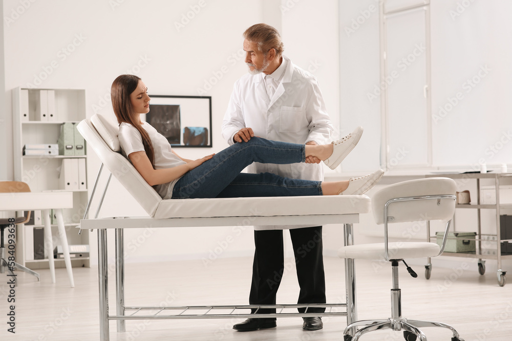 Orthopedist examining patient with injured knee in clinic Orthopedist examining patient with injured knee in clinic