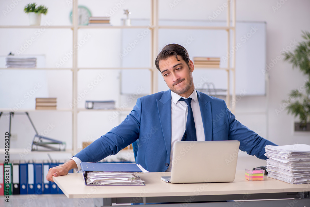 Young male employee and too much work in the office Young male employee and too much work in the office