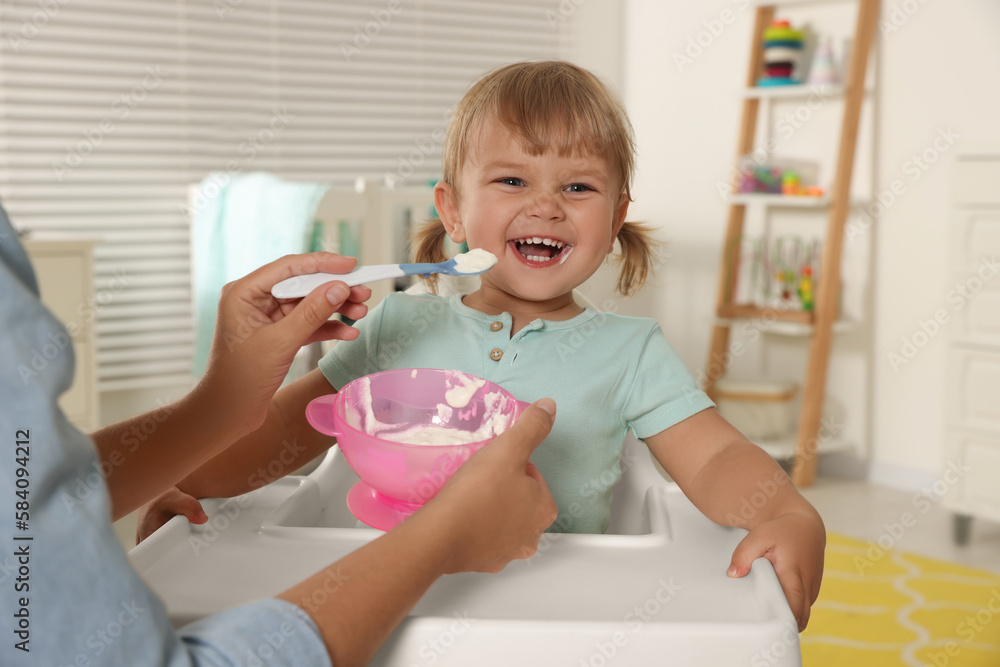 Mother feeding her cute little child with yogurt at home Mother feeding her cute little child with yogurt at home
