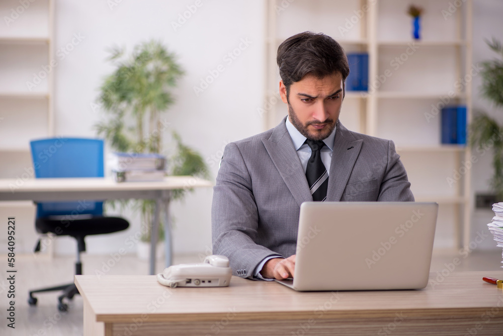 Young male employee and too much work in the office Young male employee and too much work in the office