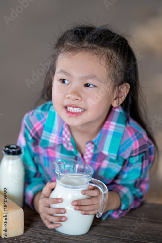 Asian girl drinking Fresh cow's milk that is produced from modern farms and dairy products. , product concepts from dairy farms and health