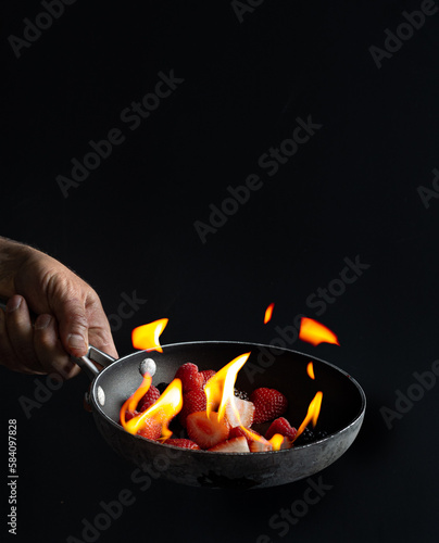 The act of flambéing strawberries, raspberries, and blackberries involves presenting the fruit at the table, soaking it in liqueur, and then setting it on fire for a dramatic effect.