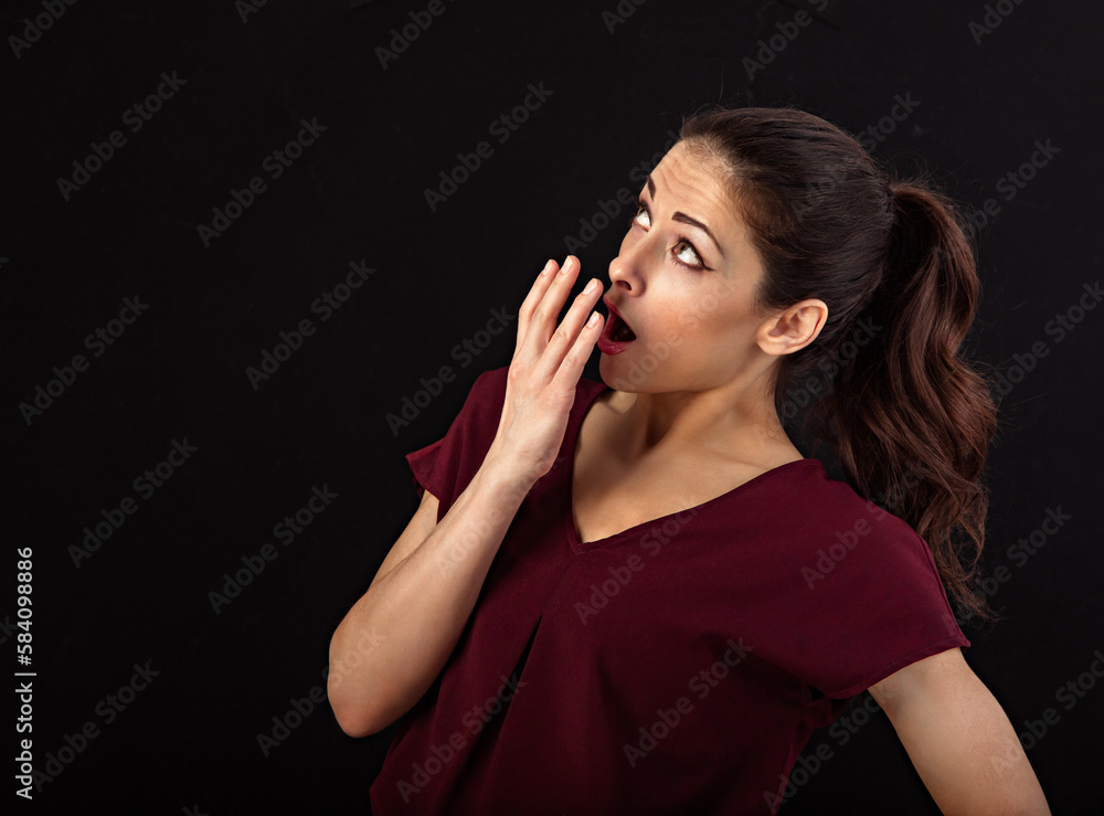 Obraz premium Beautiful excited woman with long brown healthy hair style looking up and covering the mouth the hand. Healthy lifestyle and success business. Closeup portrait