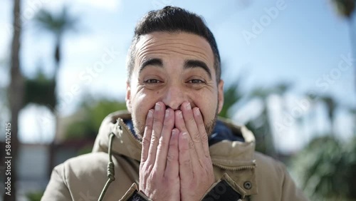 Young hispanic man standing with surprise expression at park