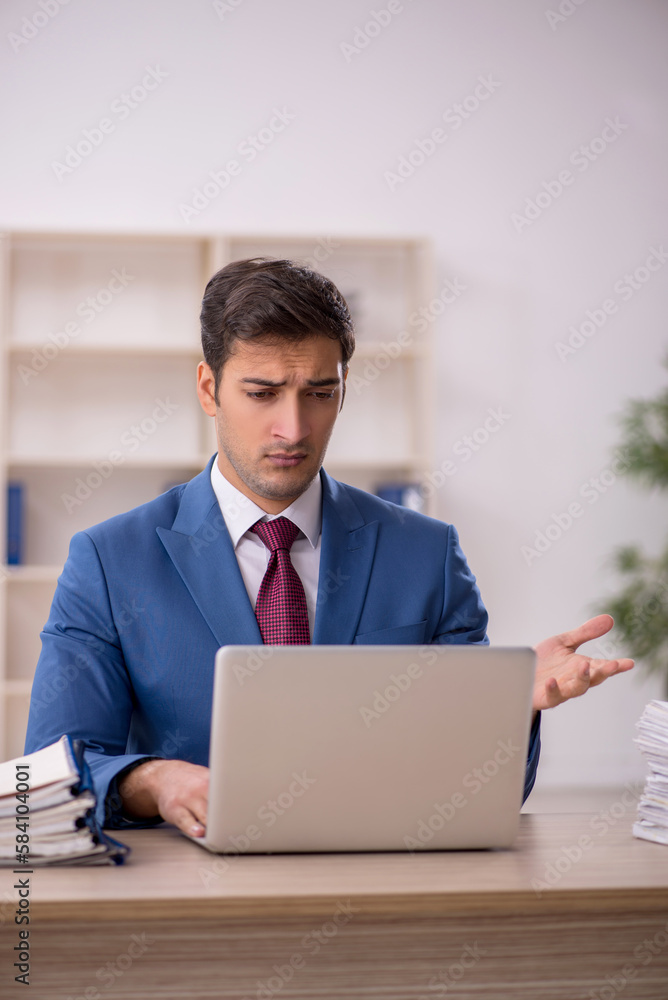 Young male employee and too much work in the office Young male employee and too much work in the office