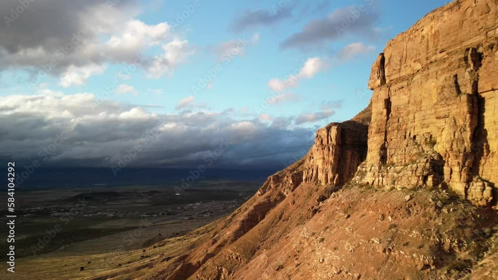 Aerial flying towards red desert cliffs in Hurricane Utah at sunset with dramatic stormy skies in spring Aerial flying towards red desert cliffs in Hurricane Utah at sunset with dramatic stormy skies in spring