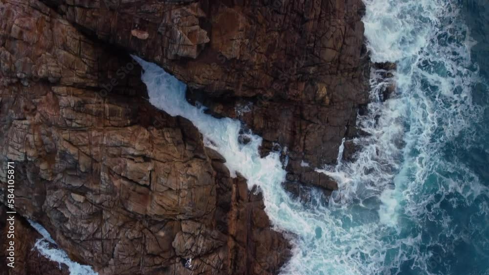 Top Down View Of Foamy Waves Splashing On Rugged Cliffs In Arteixo, Spain - drone shot Top Down View Of Foamy Waves Splashing On Rugged Cliffs In Arteixo, Spain - drone shot