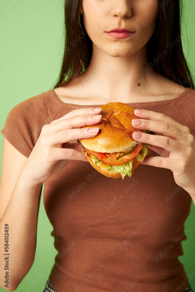 Woman holding burger with lettuce and tomato Woman holding burger with lettuce and tomato